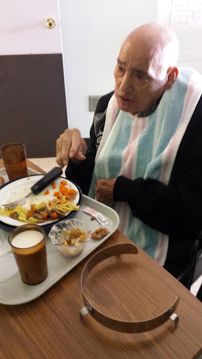 An elderly person enjoying a meal at a dining facility.