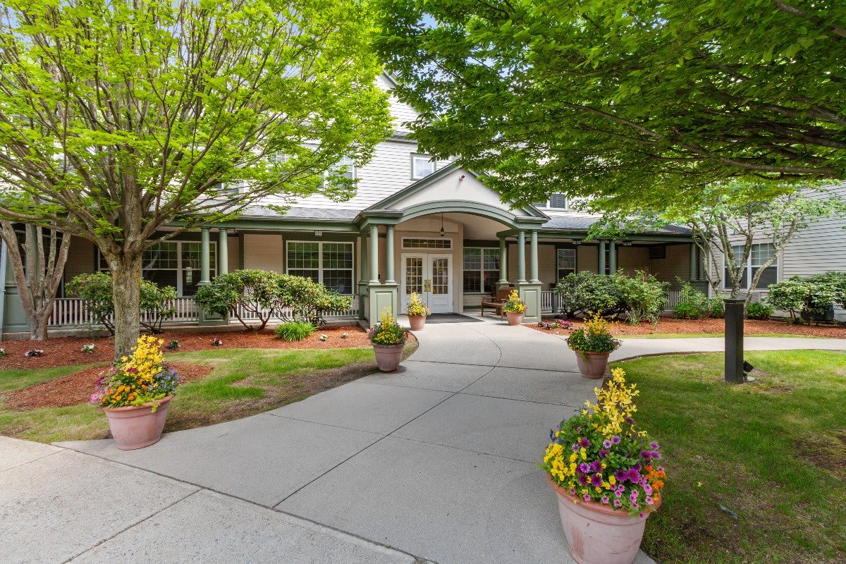 A charming house exterior with a well-maintained front yard and landscaping, featuring a pathway flanked by potted plants.
