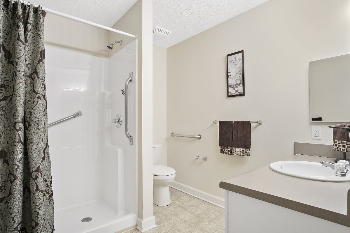A modern and clean bathroom featuring a shower, toilet, sink, and towel rack.