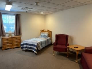 A simple bedroom with a single bed and basic furniture.