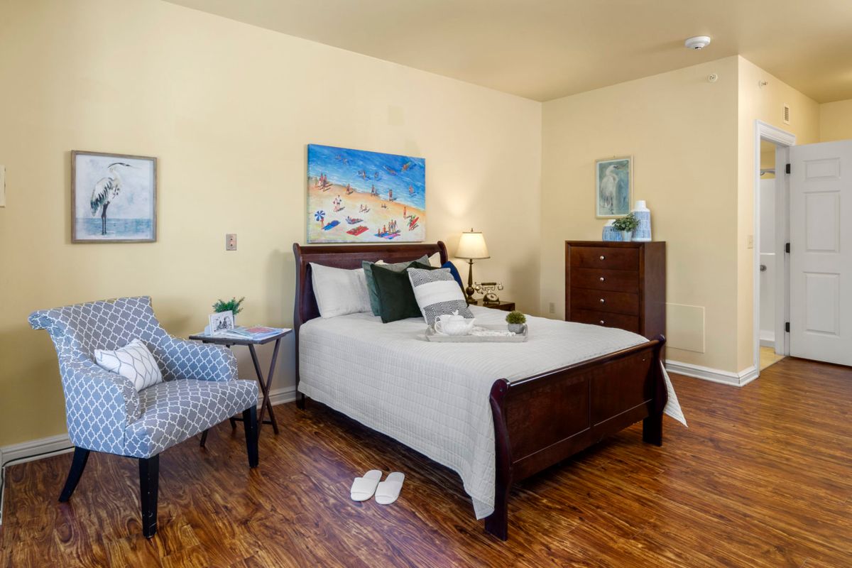 A cozy bedroom with a neatly made bed, wooden furniture, and warm lighting.
