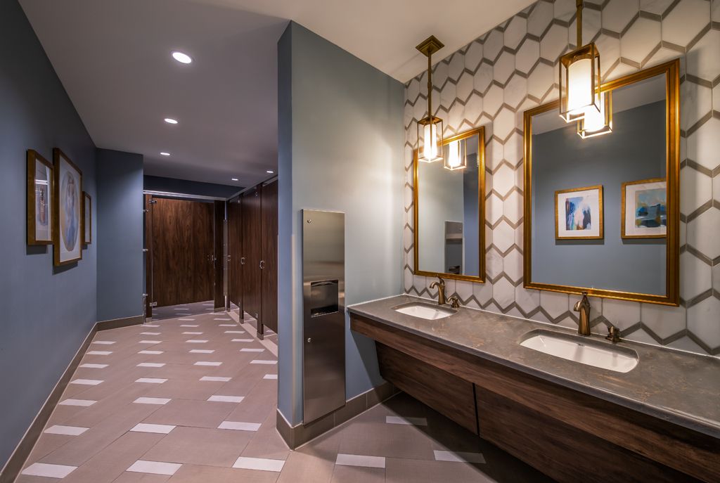 A modern bathroom with stylish vanity, mirrors, and lighting fixtures.