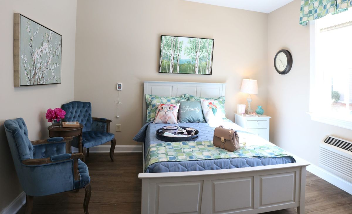 A cozy bedroom with a neatly made bed, decorative pillows, and warm lighting.
