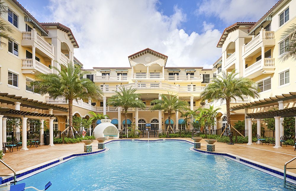 A luxurious resort featuring a large swimming pool surrounded by palm trees.