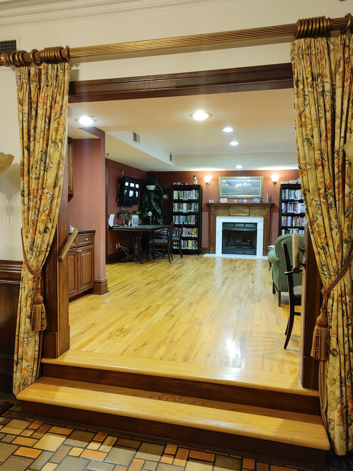 A cozy living room with hardwood floors, a fireplace, and bookshelves.