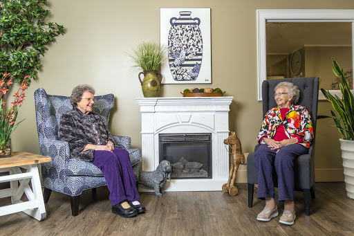 Two elderly women enjoying a conversation in a cozy living room setting.