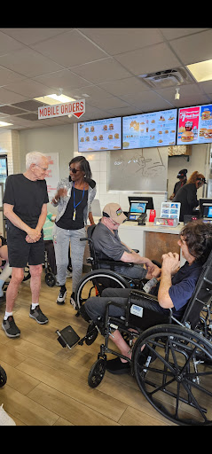 A lively scene at a fast food restaurant where individuals in wheelchairs are engaged in conversation with others.