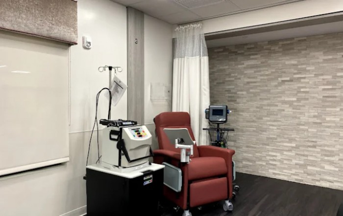 A treatment room with a reclining chair, medical equipment, and an IV stand.