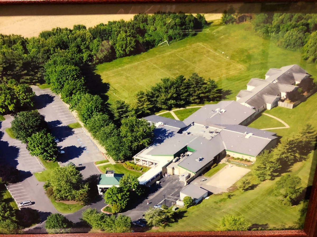 Aerial view of a large building complex surrounded by trees and greenery.
