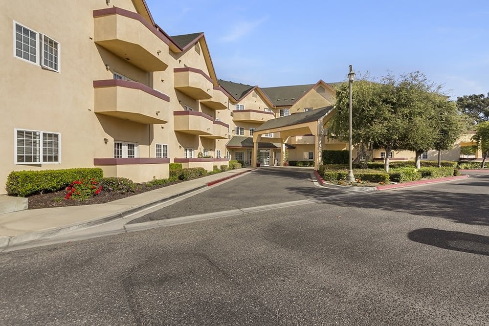 An exterior view of a hotel building with a parking area and main entrance.