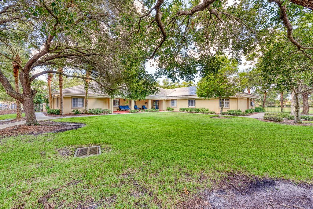 A suburban house with a well-maintained lawn and surrounding trees.