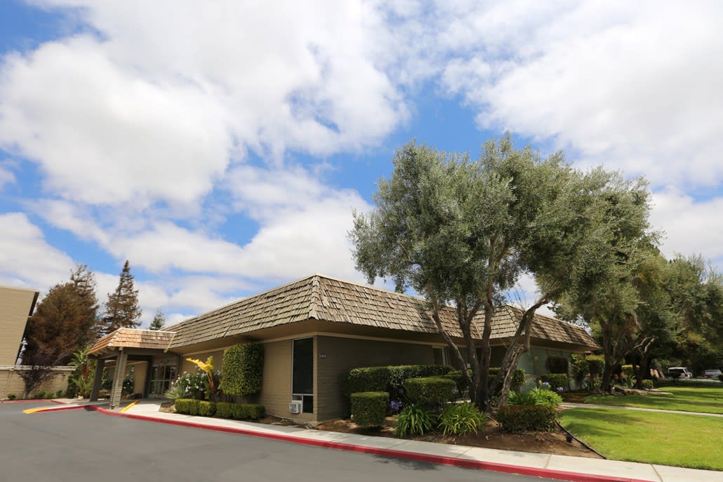 A suburban office building with a cloudy sky and surrounding trees.