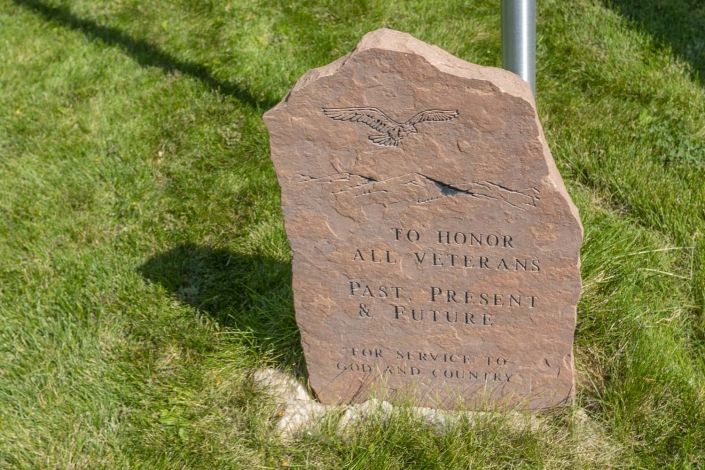 A memorial stone with engraved text on a grassy area.