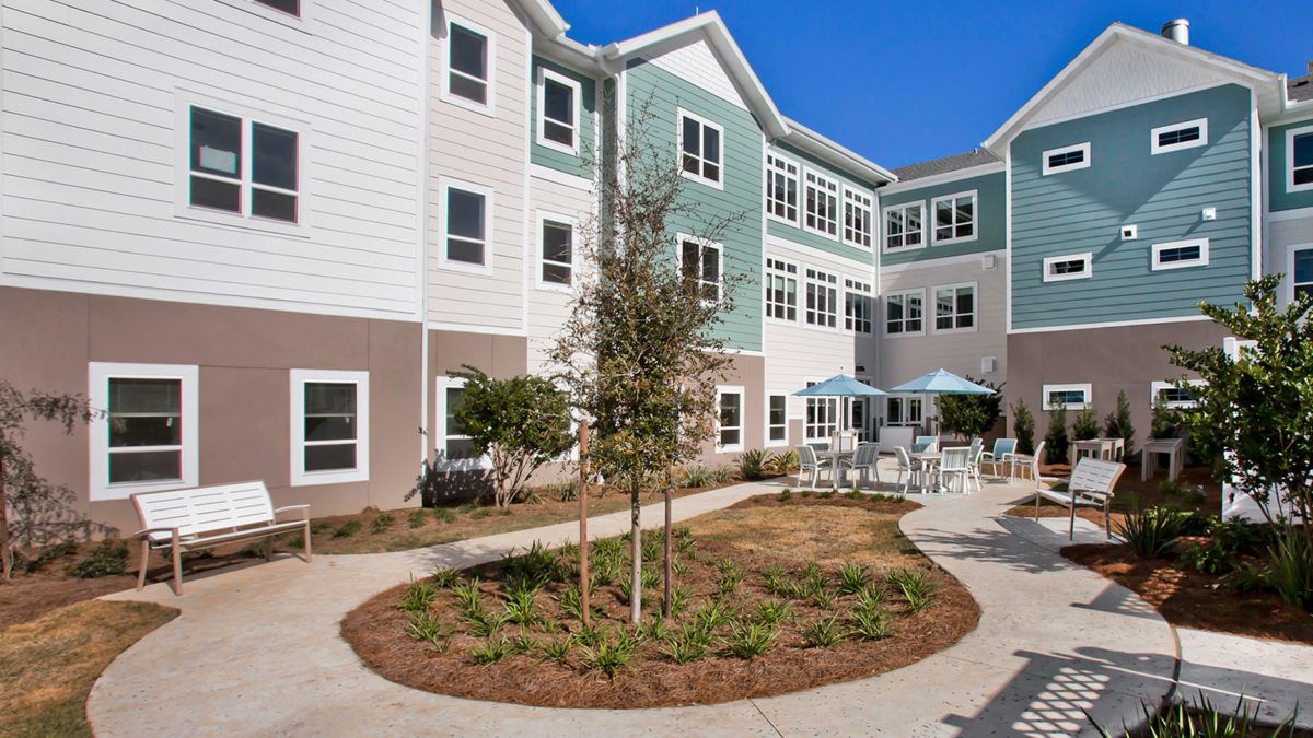 A modern residential apartment complex with a landscaped courtyard and outdoor seating area.