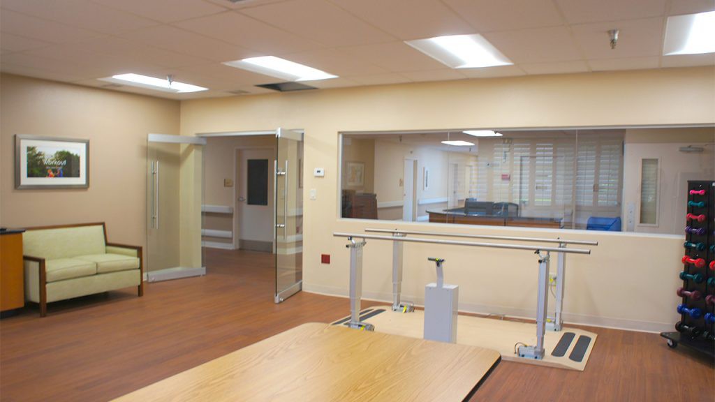 A rehabilitation therapy room with parallel bars and exercise equipment.