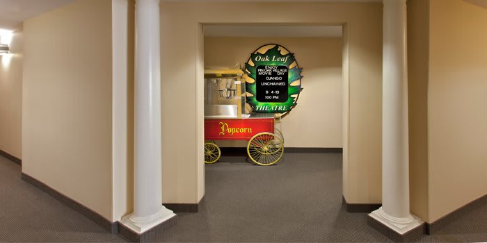 A colorful popcorn machine is placed in a hallway next to a poster advertising a wedding event.