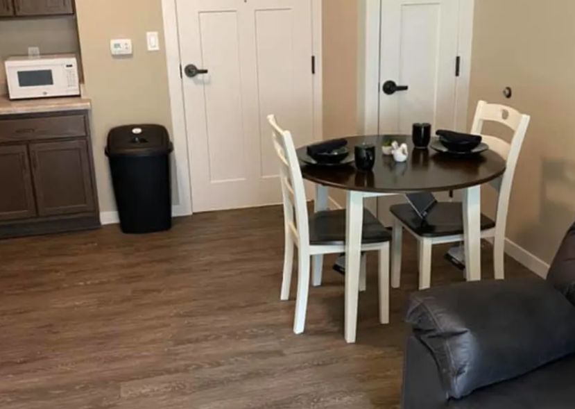 A cozy dining area with a round table and white chairs on a wooden floor.