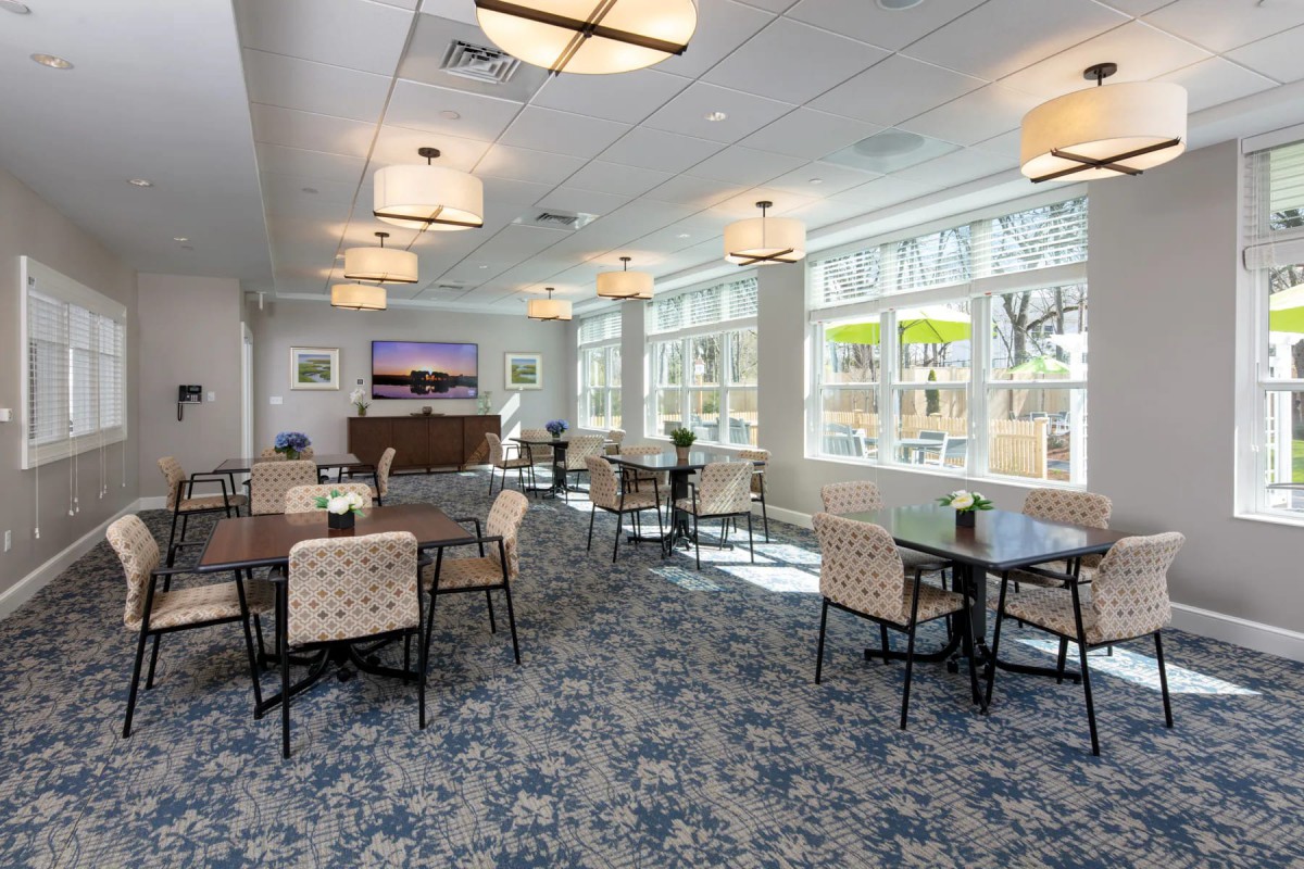 A modern dining area with tables, chairs, large windows and elegant lighting.