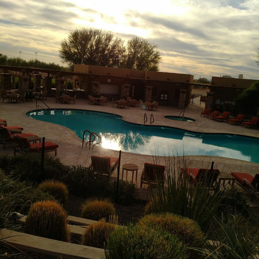A serene outdoor pool area at sunset, surrounded by nature and cozy seating.