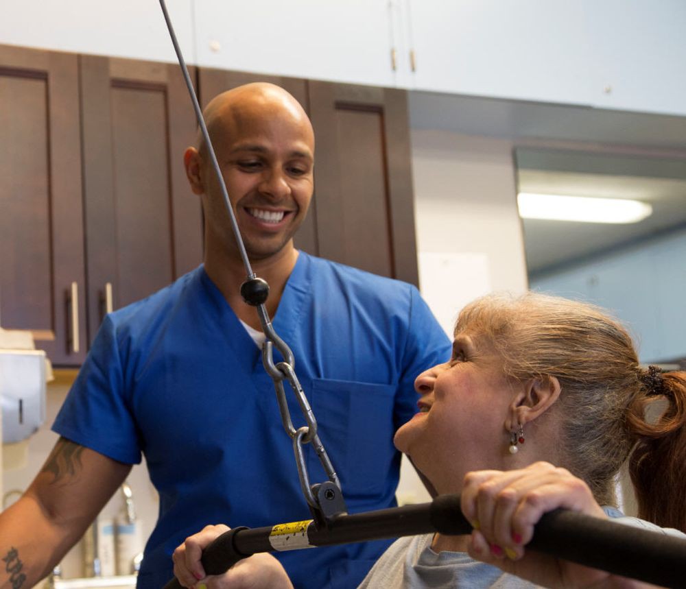 A healthcare professional assists a patient in physical therapy exercises.