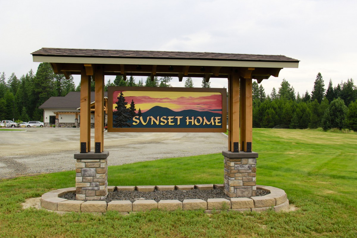 A wooden sign reading 'Sunset Home' with a landscape background.