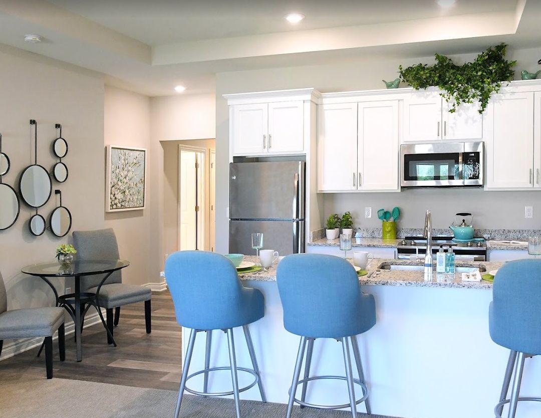 A modern kitchen with blue bar stools and stainless steel appliances.