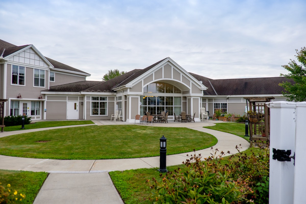A modern residential building with a well-maintained lawn and pathway leading to the entrance.