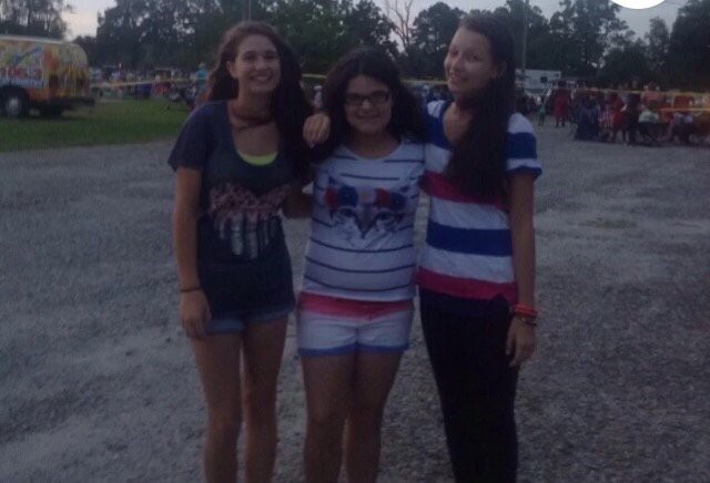 Three friends posing together outside in casual wear.