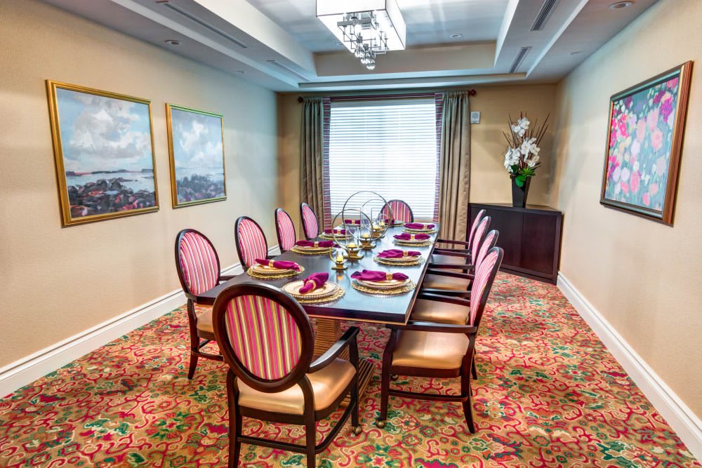 Elegant dining room setup with a long table and chairs, featuring intricate decor and artwork on the walls.