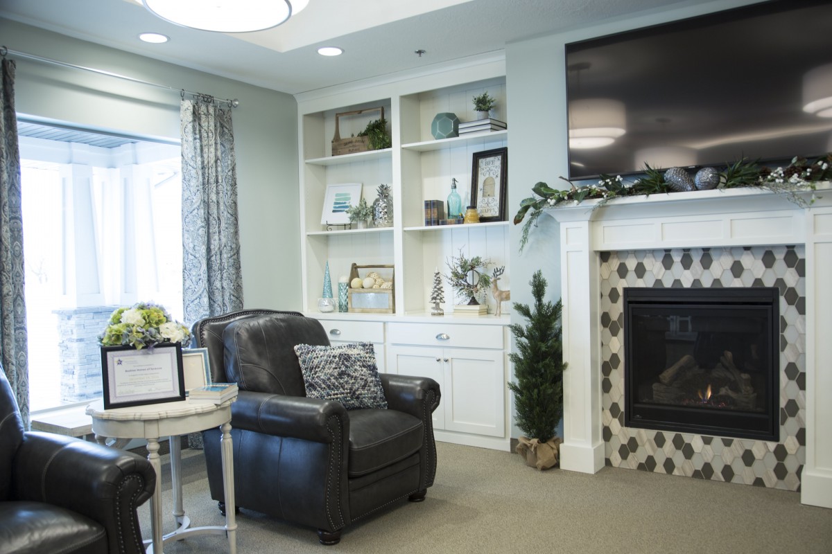 A cozy living room with a fireplace, armchair, and built-in shelves.