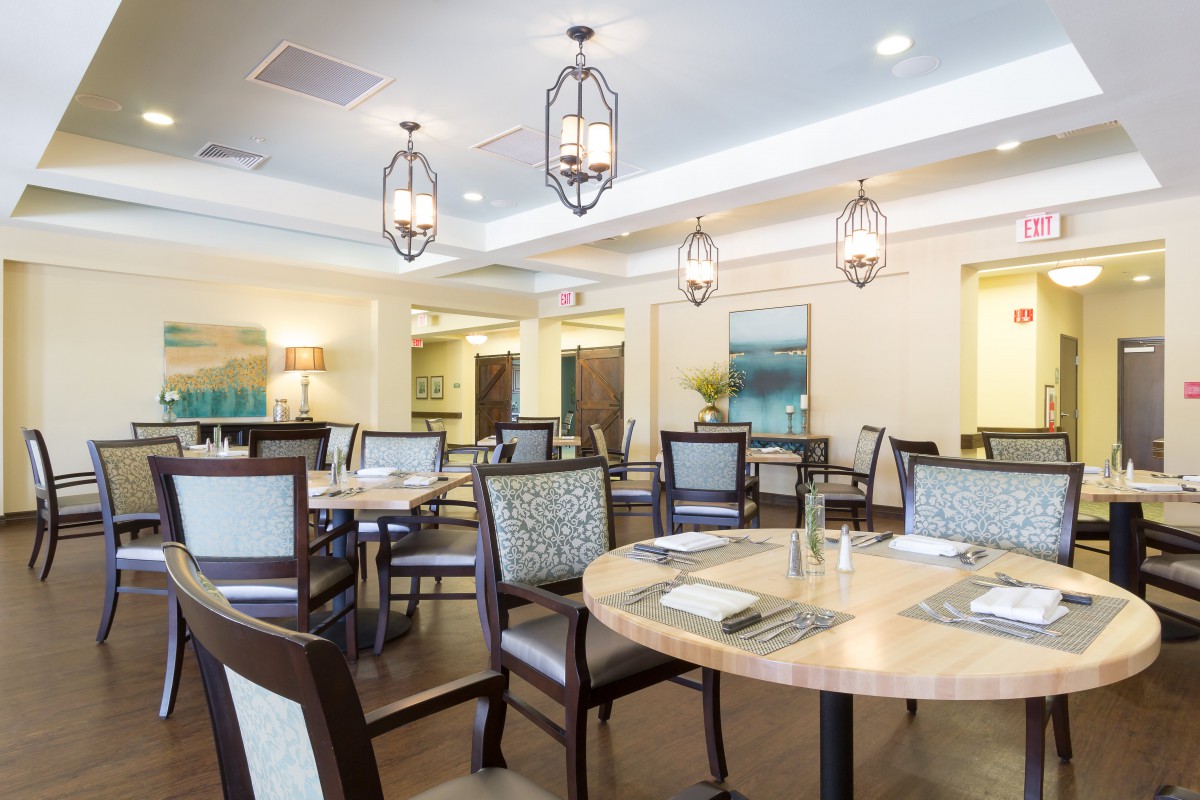 A modern dining area with elegantly arranged tables and chairs, featuring stylish lighting fixtures.