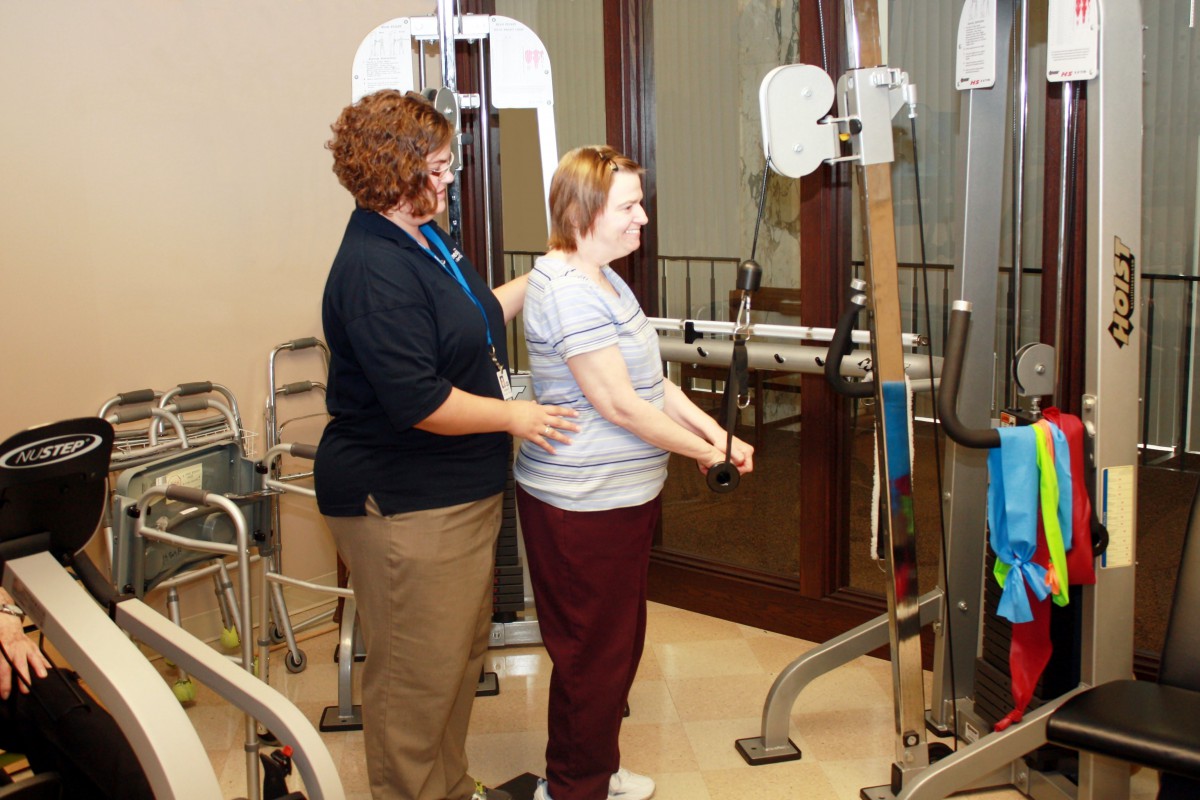 A physical therapist assists a patient with an exercise routine using specialized equipment.
