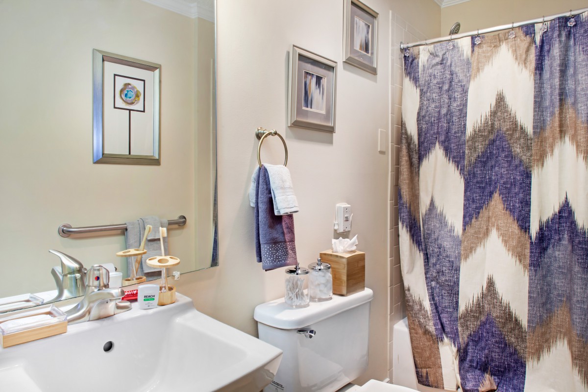 A neatly organized bathroom with a modern sink, toilet, and colorful shower curtain.