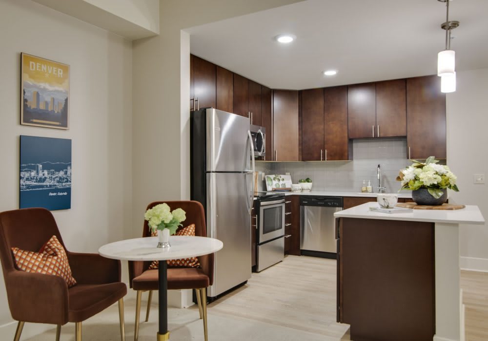 A modern kitchen with stainless steel appliances and a small dining area.