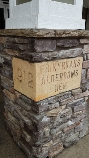 A close-up view of a stone pillar featuring an inscription that reads 'FRIKYRKANS LDERDOMS DEN' and the year '1912'.