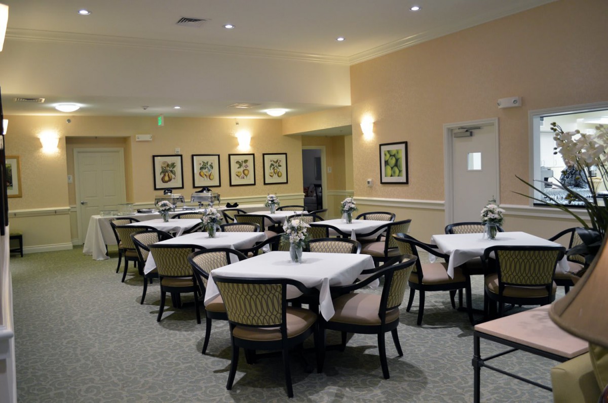 A neatly arranged dining area with tables and chairs, featuring subtle lighting and wall decor.