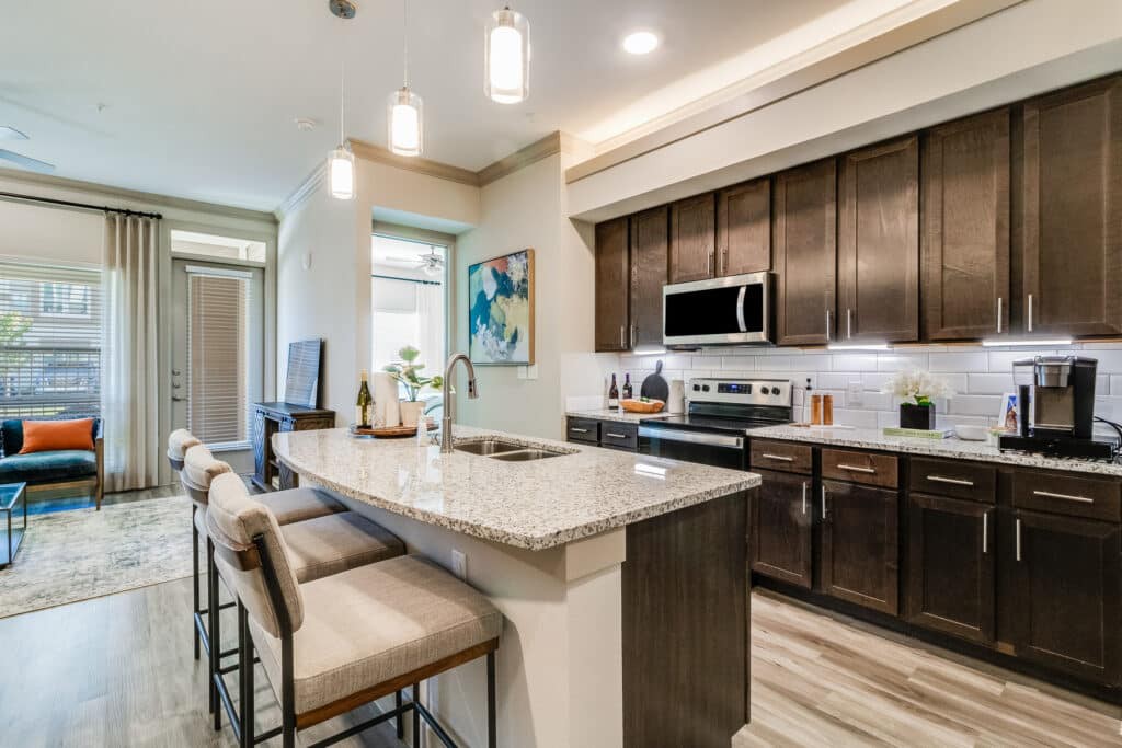A modern kitchen featuring sleek cabinetry, a central island with bar stools, and contemporary lighting fixtures.