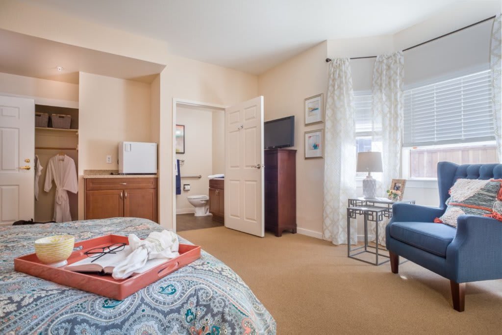 A cozy hotel room featuring a bed, television, and sitting area with stylish decor.
