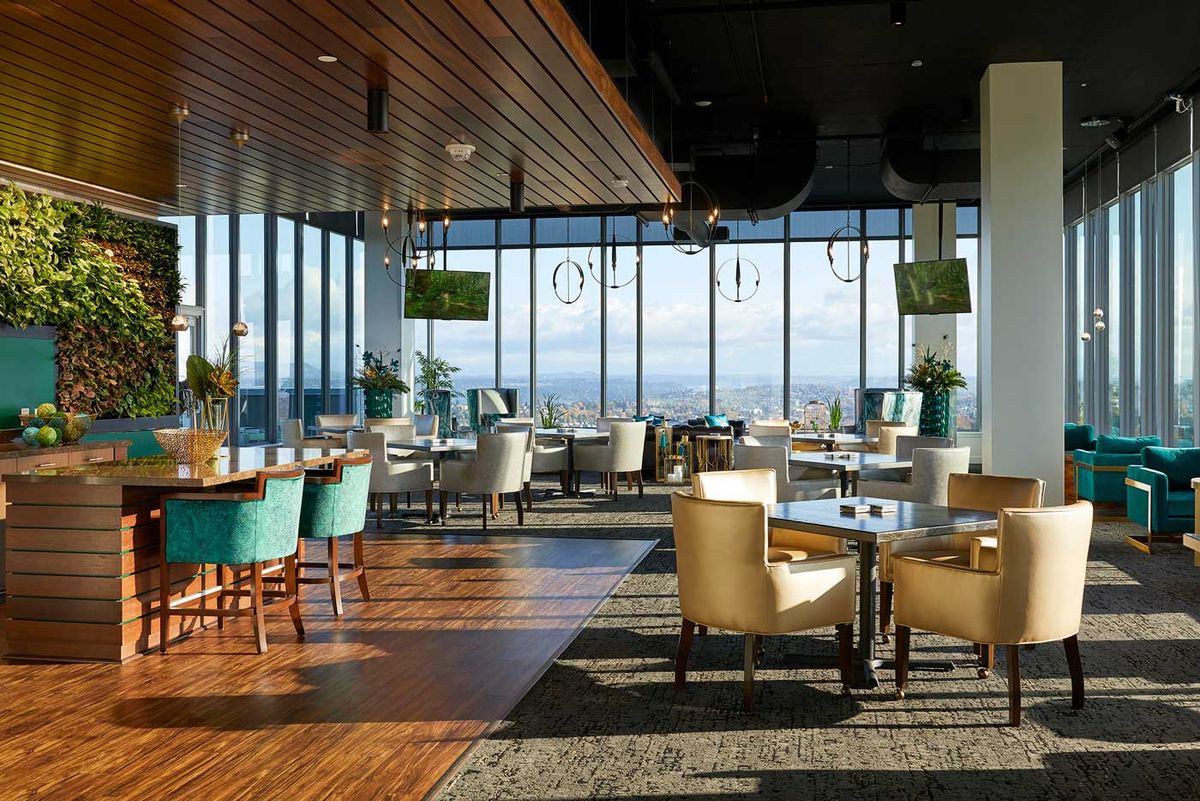 A modern restaurant interior with large windows offering a stunning city view.