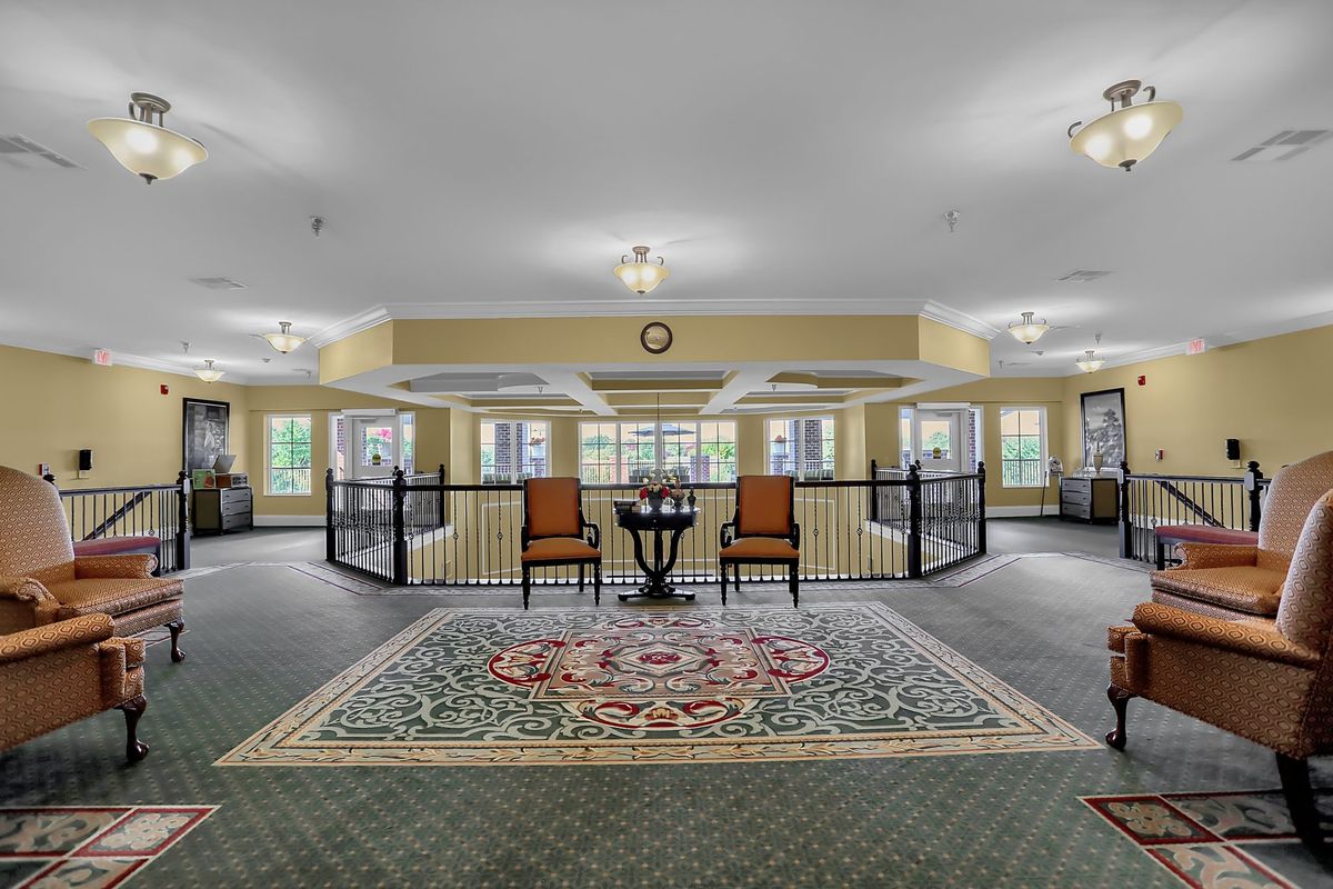A spacious lobby with a seating area, featuring two chairs and a small table on a decorative carpet.