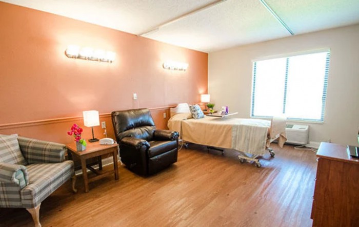 A well-lit hospital room with a bed and recliner chair, designed for patient comfort.
