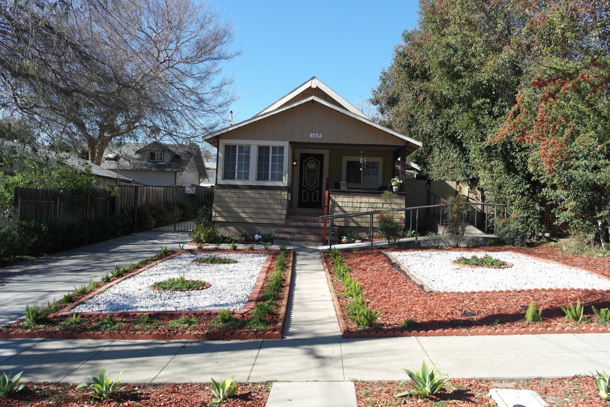 A charming house with a landscaped front yard featuring pathways and low-maintenance plants.