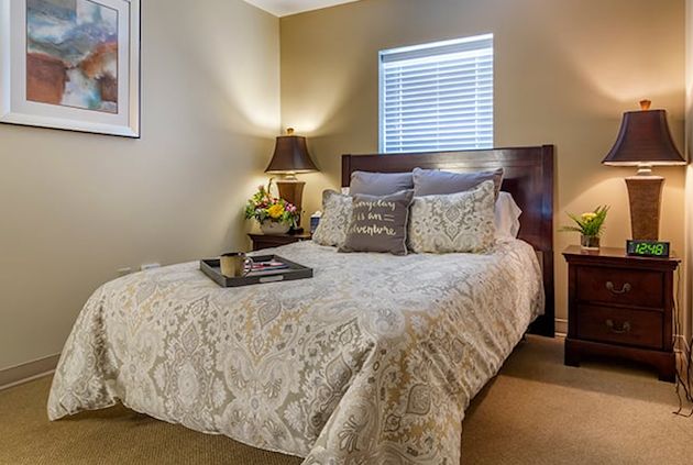 A cozy bedroom with a neatly made bed, decorative pillows, and bedside lamps.