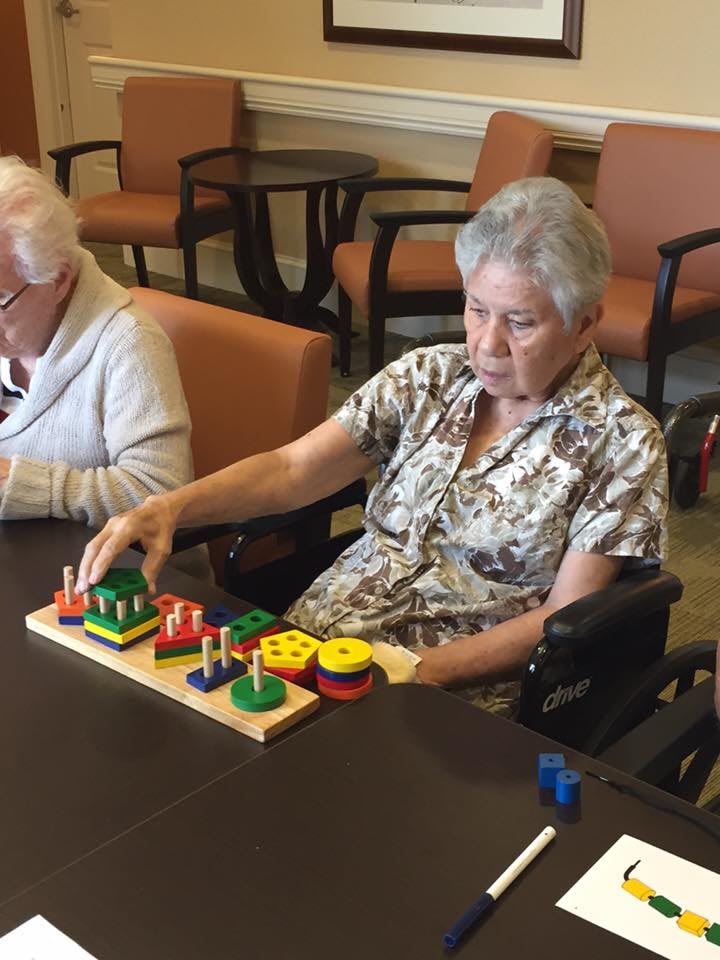 Elderly women engaging in a puzzle activity at a care home.