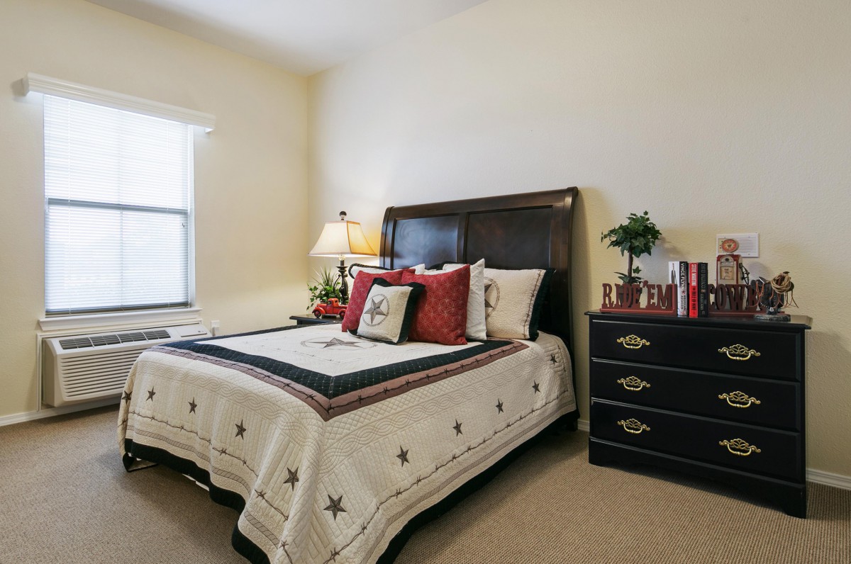 A cozy bedroom with a neatly made bed, decorative pillows, and a lamp on the nightstand.
