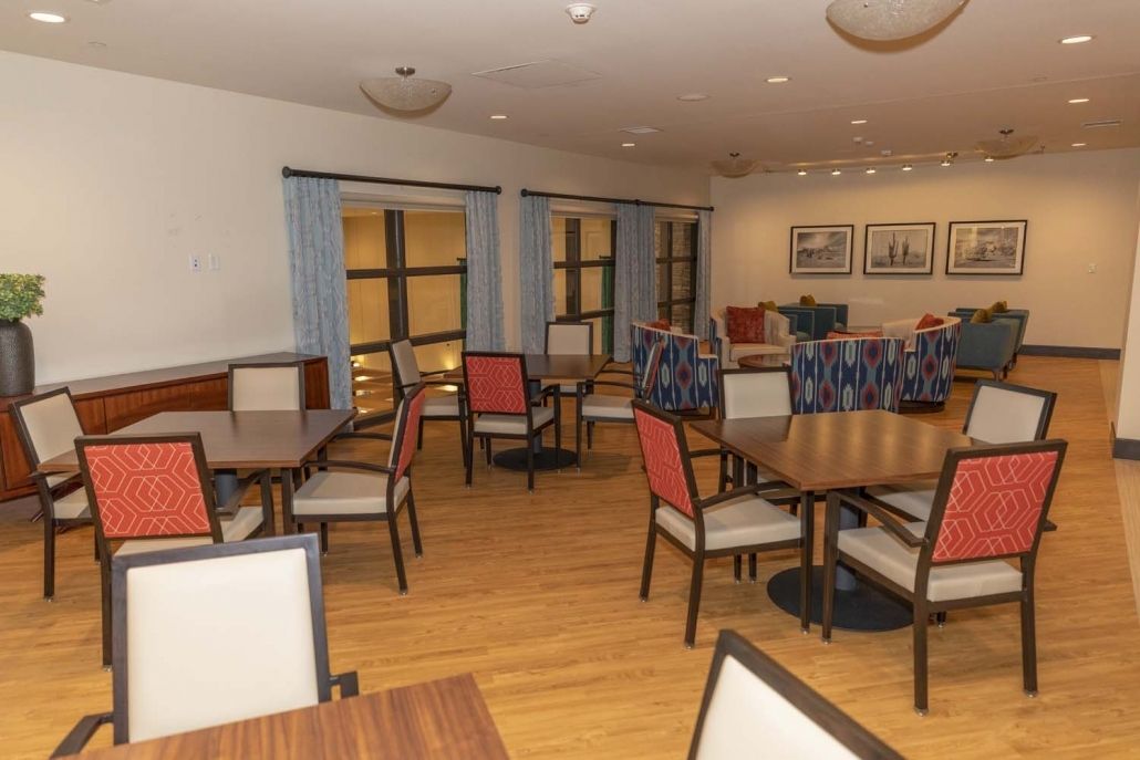 A neatly arranged dining room with several tables and chairs on a wooden floor.