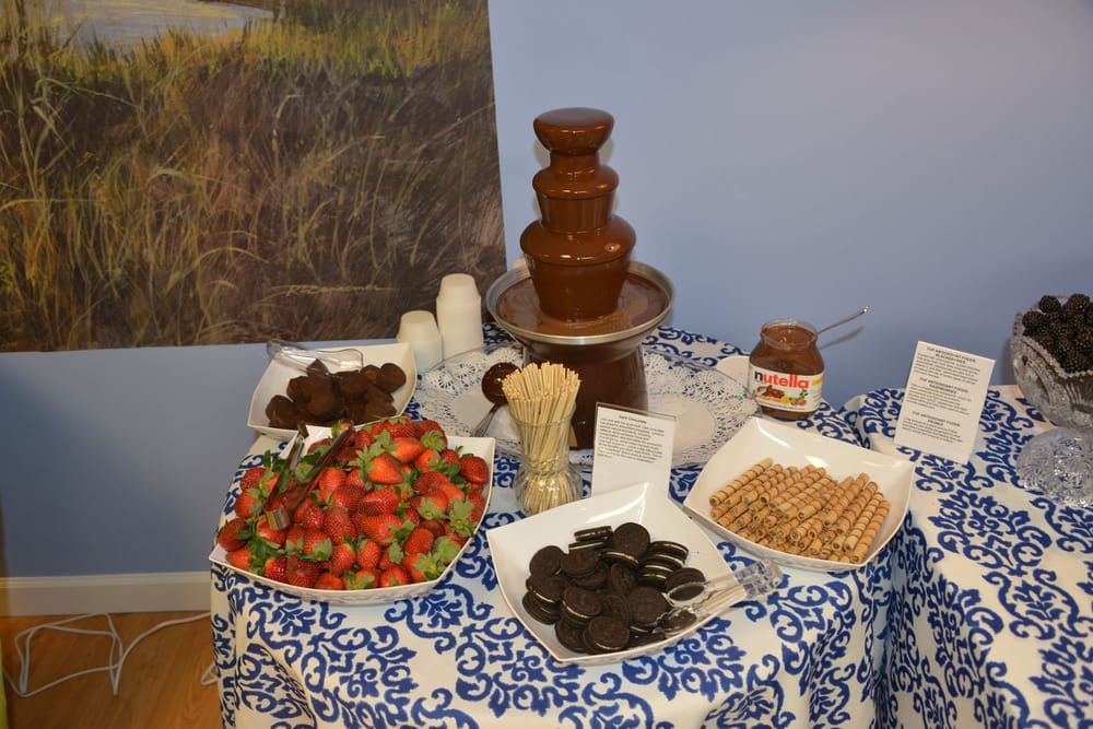 A delightful dessert table featuring a chocolate fountain surrounded by strawberries, cookies, and pretzels.