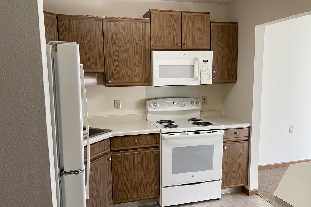 A small kitchen with wooden cabinets and white appliances.