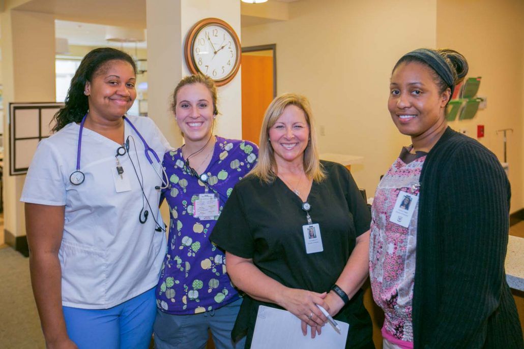 A group of healthcare professionals smiling together in a hospital setting.
