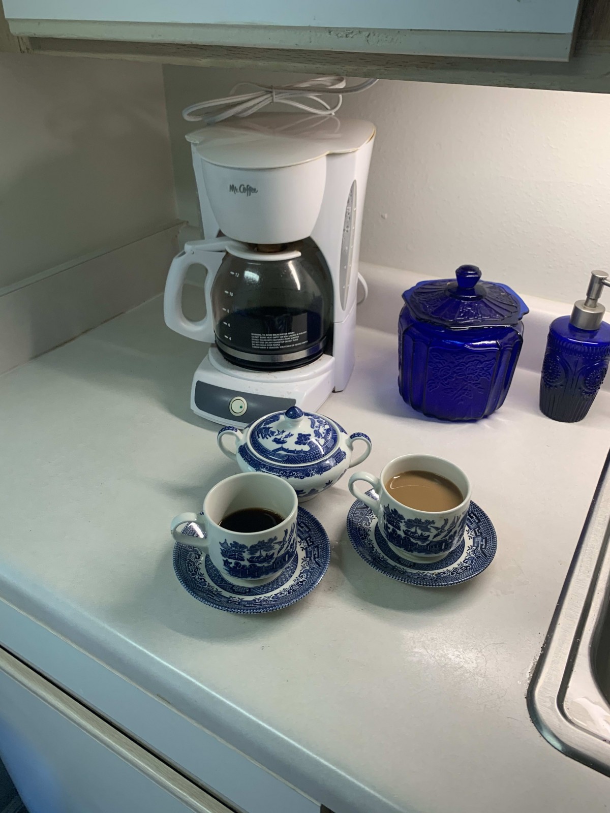 A cozy coffee setup with a machine and two cups on a kitchen counter.
